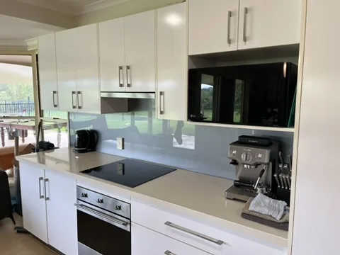 Clean white kitchen bench, cupboards, and appliances