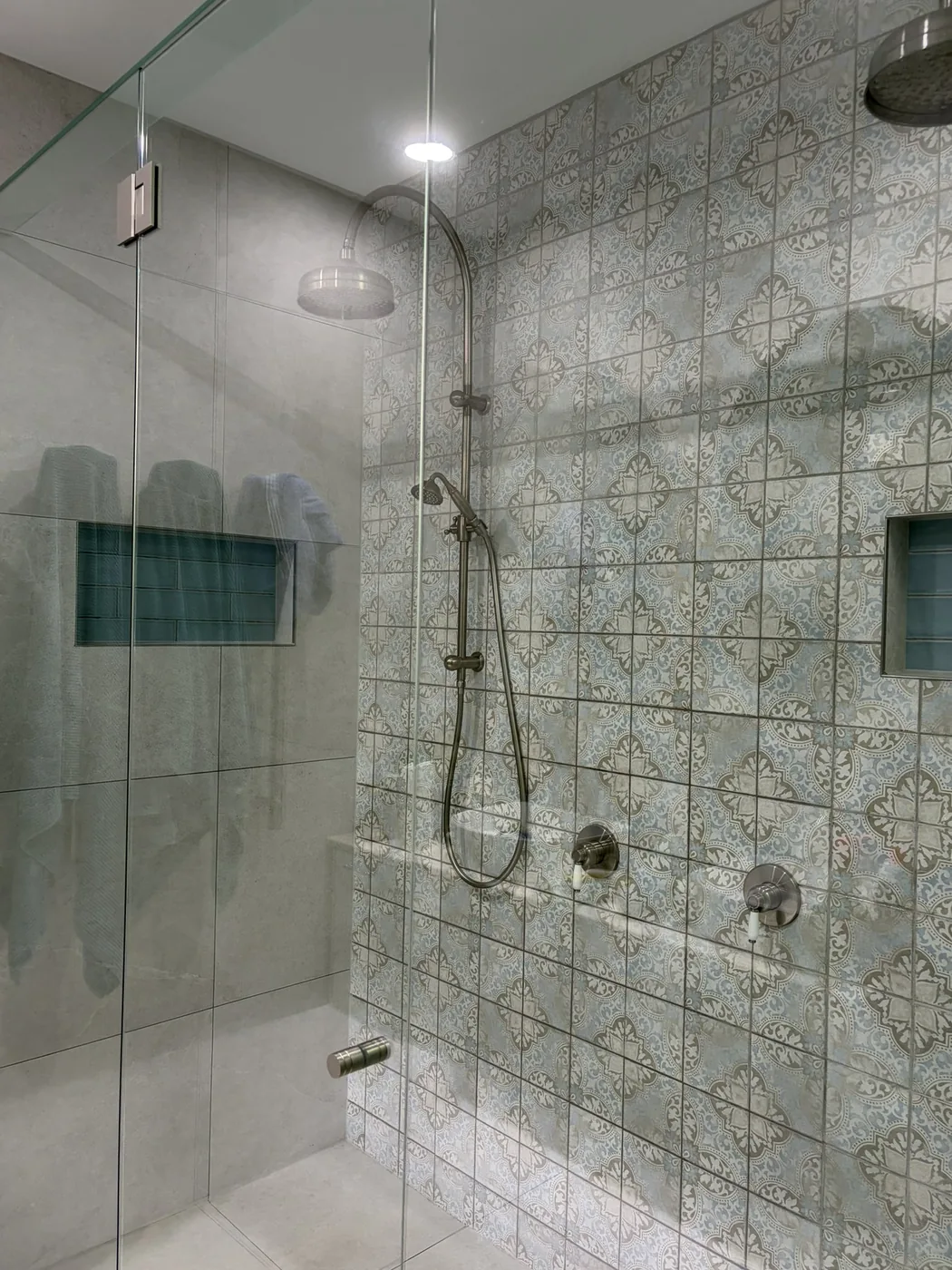 Clean tiled shower with glass and fixtures detailed